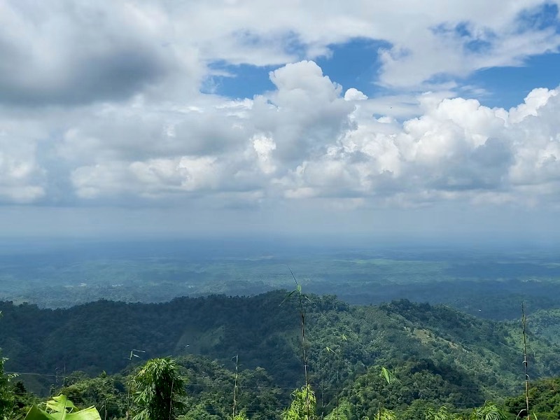 Layered forested hills fading into haze under a tall cloudy sky